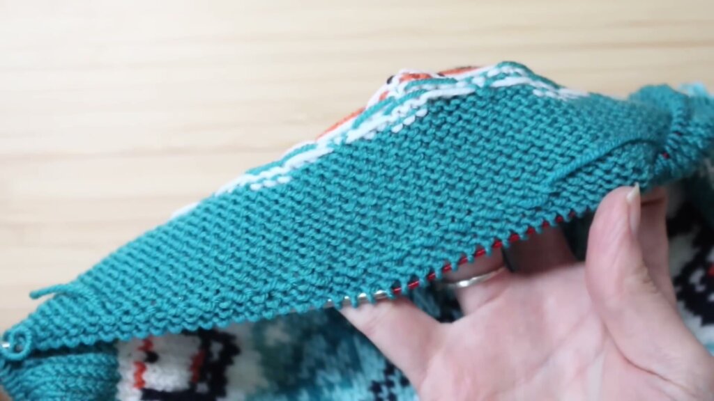 Envers du tricot montrant le fil bleu de la nouvelle pelote croisé et fixé sous les mailles