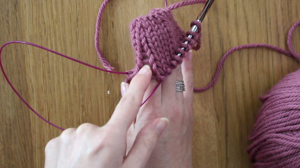 Tricot circulaire rose montrant une démarcation verticale visible entre deux rangs, l'échelle causée par une tension trop lâche au niveau de la boucle.
